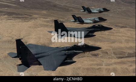 Due F-35A Lightning IIS e due F-15E Strike Eagle volano in una formazione dopo una missione di addestramento al combattimento nello spazio aereo Nevada Test and Training Range per indicare la storia dello Squadrone di Aggressor 65th e la sua riattivazione alla base dell'aeronautica di Nellis, Nevada, 9 giugno 2022. Mark Kelly, comandante del comando di combattimento aereo, ha volato la sua F-15E Strike Eagle contro il primo comandante dell'unità, il F-35, e il più recente comandante, il Lt. Col. Brandon Nauta, prima della cerimonia. (STATI UNITI Foto Air Force di Tech. SGT. Alexandre Montes) Foto Stock