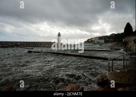 Tempesta in mare, onde alte nel vecchio porto di pescatori con faro a Cassis, Provenza, Francia Foto Stock