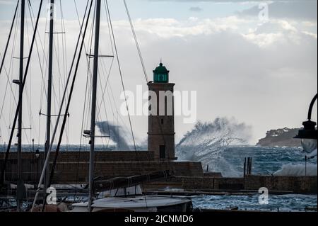 Tempesta in mare, onde alte nel vecchio porto di pescatori con faro a Cassis, Provenza, Francia Foto Stock