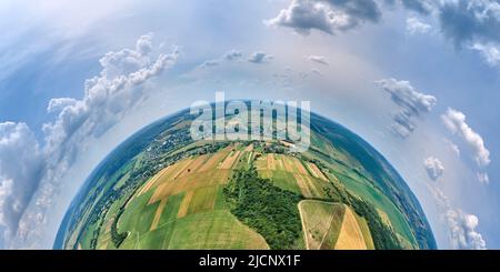 Vista aerea dall'alta quota del piccolo pianeta terra con campi agricoli verdi e gialli coltivati con colture in crescita in luminoso giorno d'estate Foto Stock