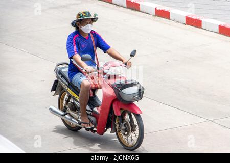 SAMUT PRAKAN, THAILANDIA, 06 2022 MAGGIO, Un uomo con maschera di faccia guida una moto sulla strada Foto Stock