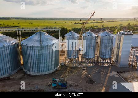 Vista aerea di silos industriali ventilati per lo stoccaggio a lungo termine di cereali e semi oleosi. Elevatore in metallo per l'essiccazione del grano in zona agricola Foto Stock