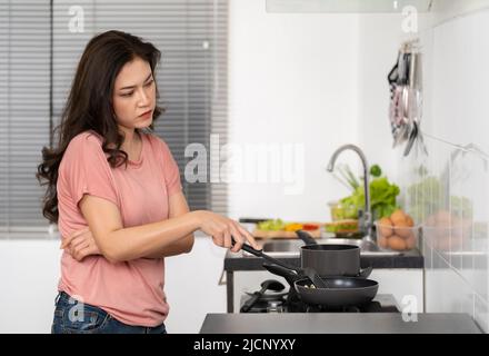 giovane donna stanca che cucinava e preparava il cibo in cucina a casa Foto Stock