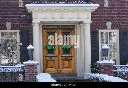 Tradizionale casa in mattoni più antica con ingresso portico e decorazione natalizia su legno grano doppio porta anteriore Foto Stock