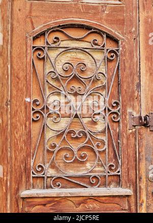 Vecchia porta in legno con griglia vintage in metallo Foto Stock