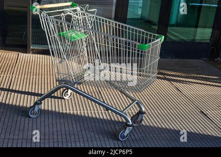 Carrello per prodotti alimentari in piedi vicino all'ingresso del supermercato sulla strada Foto Stock