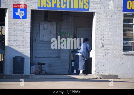 Un uomo in sovrappeso al lavoro in un negozio di riparazione auto a Irving, Texas, che fornisce anche ispezioni statali Foto Stock