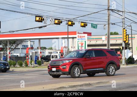 SUV svolta a sinistra su Irving Blvd. A Dallas, Texas, con un minimarket 7-11 e un distributore di benzina Exxon sullo sfondo Foto Stock