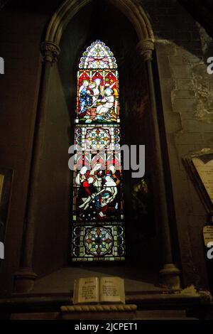 Luce attraverso rosette di vetro colorate, che rappresentano immagini religiose Foto Stock