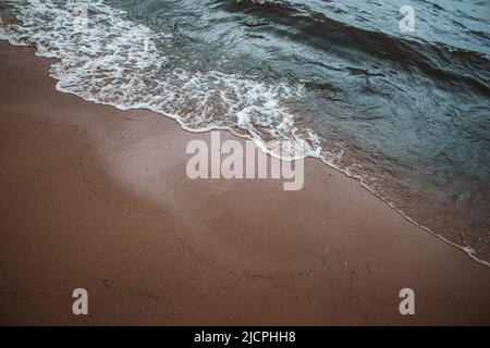 Le onde si lavano sulla spiaggia di sabbia Foto Stock