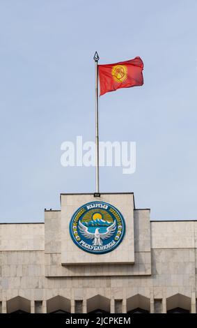 Bishkek, Kirghizistan - 21 ottobre 2021: Emblema nazionale e bandiera del Kirghizistan sulla costruzione della Casa Bianca Foto Stock