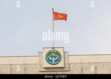 Bishkek, Kirghizistan - 21 ottobre 2021: Emblema nazionale e bandiera del Kirghizistan sulla costruzione della Casa Bianca Foto Stock