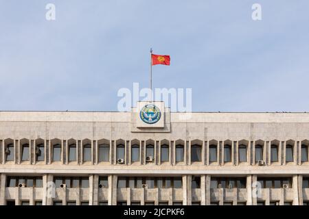 Bishkek, Kirghizistan - 21 ottobre 2021: Emblema nazionale e bandiera del Kirghizistan sulla costruzione della Casa Bianca Foto Stock