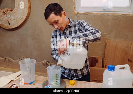 Carpentiere preparazione resina epossidica. Processo di fabbricazione di una resina artigianale e tavola di legno. Foto Stock