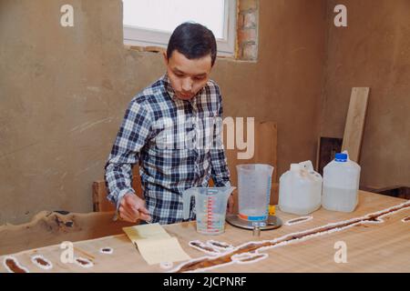 Carpentiere preparazione resina epossidica. Processo di fabbricazione di una resina artigianale e tavola di legno. Foto Stock