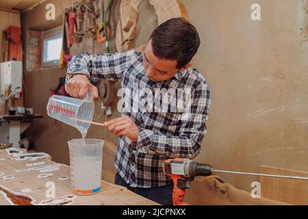 Carpentiere preparazione resina epossidica. Processo di fabbricazione di una resina artigianale e tavola di legno Foto Stock