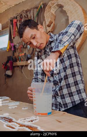 Carpentiere preparazione resina epossidica. Processo di fabbricazione di una resina artigianale e tavola di legno Foto Stock