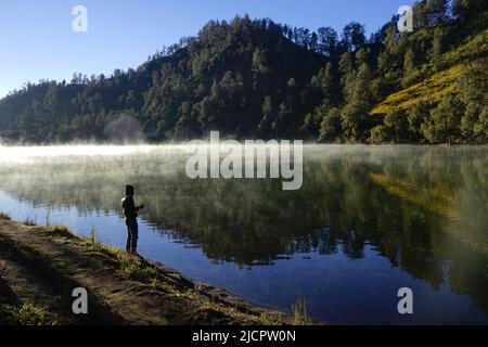 Un uomo a Ranu Kumbolo con la luce del sole sullo sfondo Foto Stock