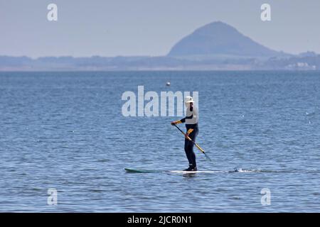 Portobello, Edimburgo, Scozia, Regno Unito. 15.06.2022. L'onda di calore che attrarre i pedalò fuori sopra al Firth di Forth, è stata alcune settimane da quando alcuno si è avventurato fuori a causa delle recenti condizioni nuvolose fredde. La temperatura di questa mattina di 18 gradi ha portato alcuni fuori per l'esercitazione. Nella foto: Paddleboarder maschio con la legge Berwick sullo sfondo. Credit: Scottisgriative/alamy live news. Foto Stock