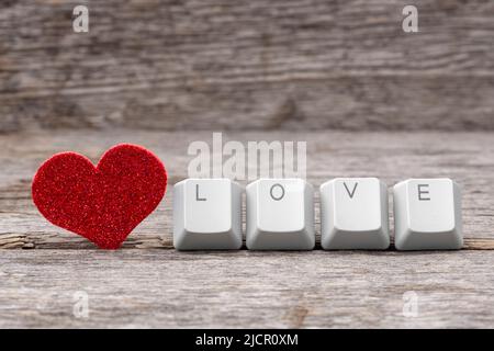 Il cuore rosso e l'AMORE della parola scritto sui tasti della tastiera. Internet dating concetto. Foto Stock