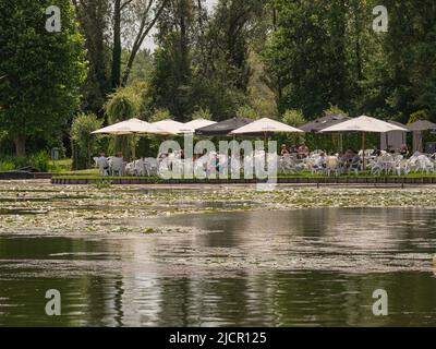 Meerdonk, Belgio, 12 giugno 2022, la gente è seduta su una terrazza sotto grandi ombrelloni godendo l'acqua Foto Stock