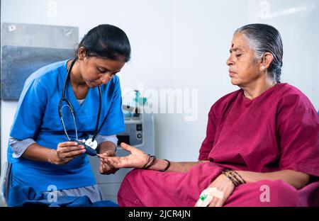 medico o infermiera controllo del livello di zucchero o diabete di donna malata ospedalizzata in operazione letto di abito - concetto di monitoraggio della salute e trattamento e. Foto Stock