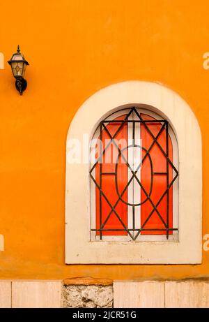 Finestra ad arco con grata di ferro posta in intonaco arancione a Roma. Foto Stock
