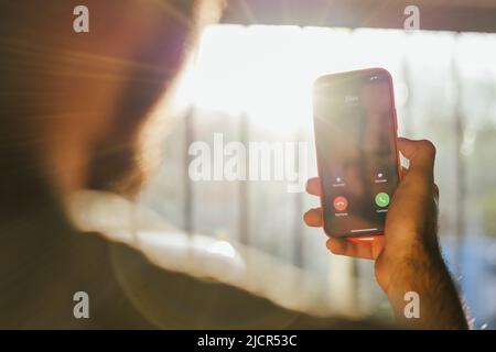 Persona che cerca un numero tra i suoi contatti telefonici. Chiamate ai client. Giovane uomo che registra un numero sul suo cellulare Foto Stock