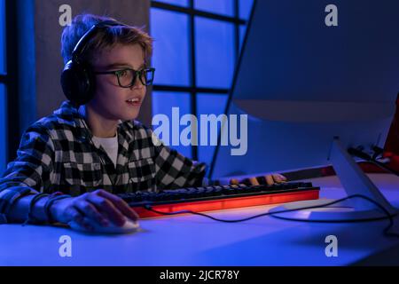 Giovane ragazzo di videogamer con cuffie che gioca al video gioco del computer. Foto Stock