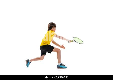 Ritratto dinamico di teen, ragazzo sportivo giocando a tennis isolato su sfondo bianco studio. Concetto di sport, realizzazioni, hobby, abilità Foto Stock