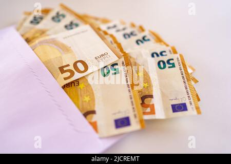 Un sacco di cinquanta banconote in euro farcite in una busta di carta bianca Foto Stock