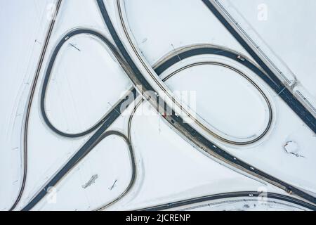 Vista dall'alto dell'incrocio stradale in inverno. L'intersezione è simile al numero 8. Traffico auto, trasporto tra la neve. Foto Stock