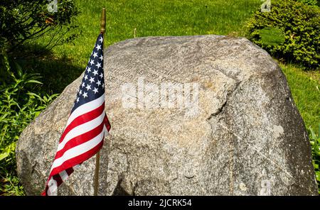 Bandiera americana e pietra 'eretto in memoria degli uomini e delle donne che hanno servito il loro paese 1754 a 1954' su un villaggio verde del New England Foto Stock