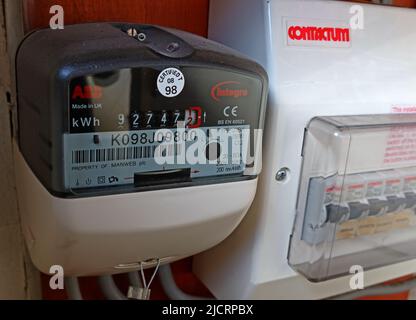 Contatore elettrico domestico, che mostra i costi di carburante aumentati, per kWh, accanto all'unità di consumo Foto Stock