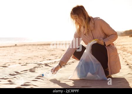 Donna assistente, attivista pulizia spiaggia sabbiosa vicino oceano da rifiuti di plastica, spazzatura. Eco turismo, inquinamento marino Foto Stock