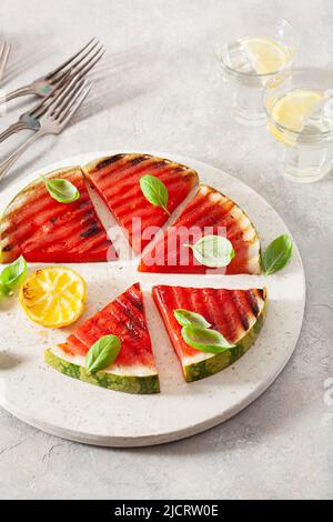 fette di anguria grigliate con limone e basilico. dessert estivo Foto Stock