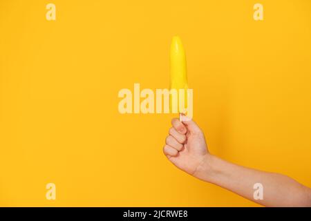 Mano del bambino che tiene il gelato sul bastone nella forma del razzo sullo sfondo giallo Foto Stock