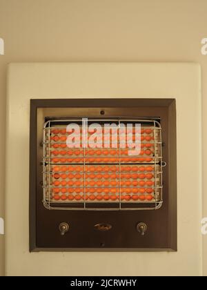 Il riscaldatore elettrico Belling 1950s o 1960s, montato a parete, a doppio controllo, è mostrato in funzione e in arancione brillante. Foto Stock