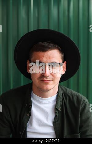 Buon uomo intelligente. Ritratto di bello sorridente elegante Hipster modello Lamberseual. Uomo vestito di occhiali e cappello nero. Maschio sul backgrou moderno Foto Stock