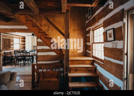Interno di rustico casetta in legno mostrando scale e cucina. Foto Stock