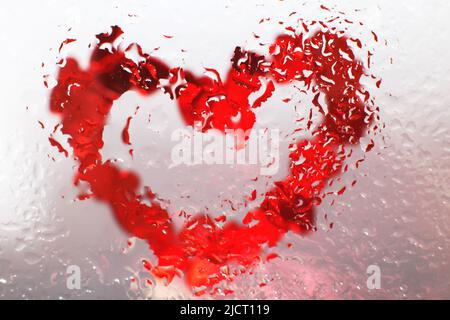 cuore rosso sotto vetro con gocce d'acqua. sfondo astratto con gocce d'acqua e cuore dipinto sulla superficie. San Valentino sfondo, amore, data co Foto Stock