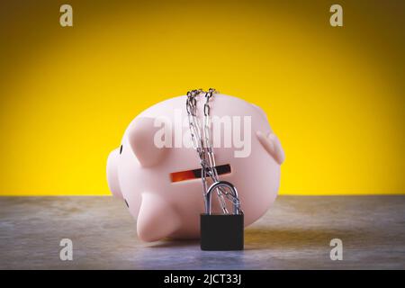 Chiudiosassata. Risparmio bloccato. La banca del piggy è legata con una catena e bloccata. Concetto di protezione dei soldi. Foto Stock