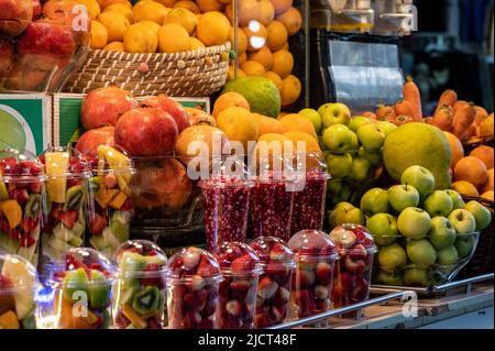 La frutta viene raccolta e impilata sul bancone del mercato per spremere il succo su una pressa manuale. Frutta assortita in un bicchiere trasparente. Foto Stock