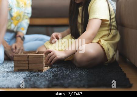 Ragazza che gioca in legno jenga costruttore con nonna a casa. Attività ricreative per i bambini a casa. Foto Stock