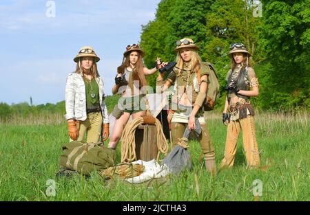 Quattro ragazze sono viste come esploratori. Sono visti al loro campeggio nella natura selvaggia all'aperto. Indossano cappelli safari e abiti cachi. Foto Stock