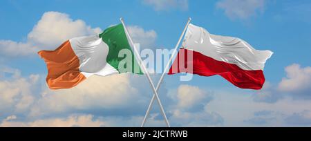 Due bandiere incrociate Irlanda e Polonia che ondeggiano nel vento a cielo nuvoloso. Concetto di rapporto, dialogo, viaggiare tra due paesi. 3d illustrazione Foto Stock