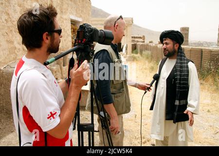 Bernard Smith, centro, giornalista, e ben Foley, a sinistra, Cameraman, con al Jazeera English News Channel intervista un cittadino afghano locale a Kajaki, Hel Foto Stock