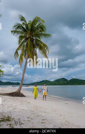 Coppia di uomini e donne che camminano sulla spiaggia all'isola Koh Yao Yai Thailandia, spiaggia con sabbia bianca e palme. Foto Stock