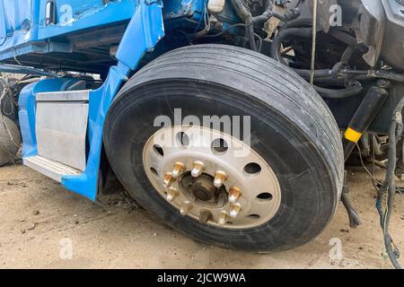 Primo piano di camion abbandonato in un deposito, un camion blu con una ruota distrutta e altre parti dopo un incidente sulla strada, grande automobile rotta su un cortile spazzatura. Foto Stock