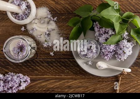 composizione di vari contenitori con zucchero lilla e rami di lilla da giardino su un tavolo di legno villaggio. vista dall'alto Foto Stock